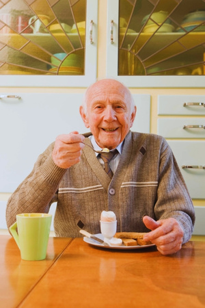 apoio sénior - idoso sorridente a tomar pequeno-almoço